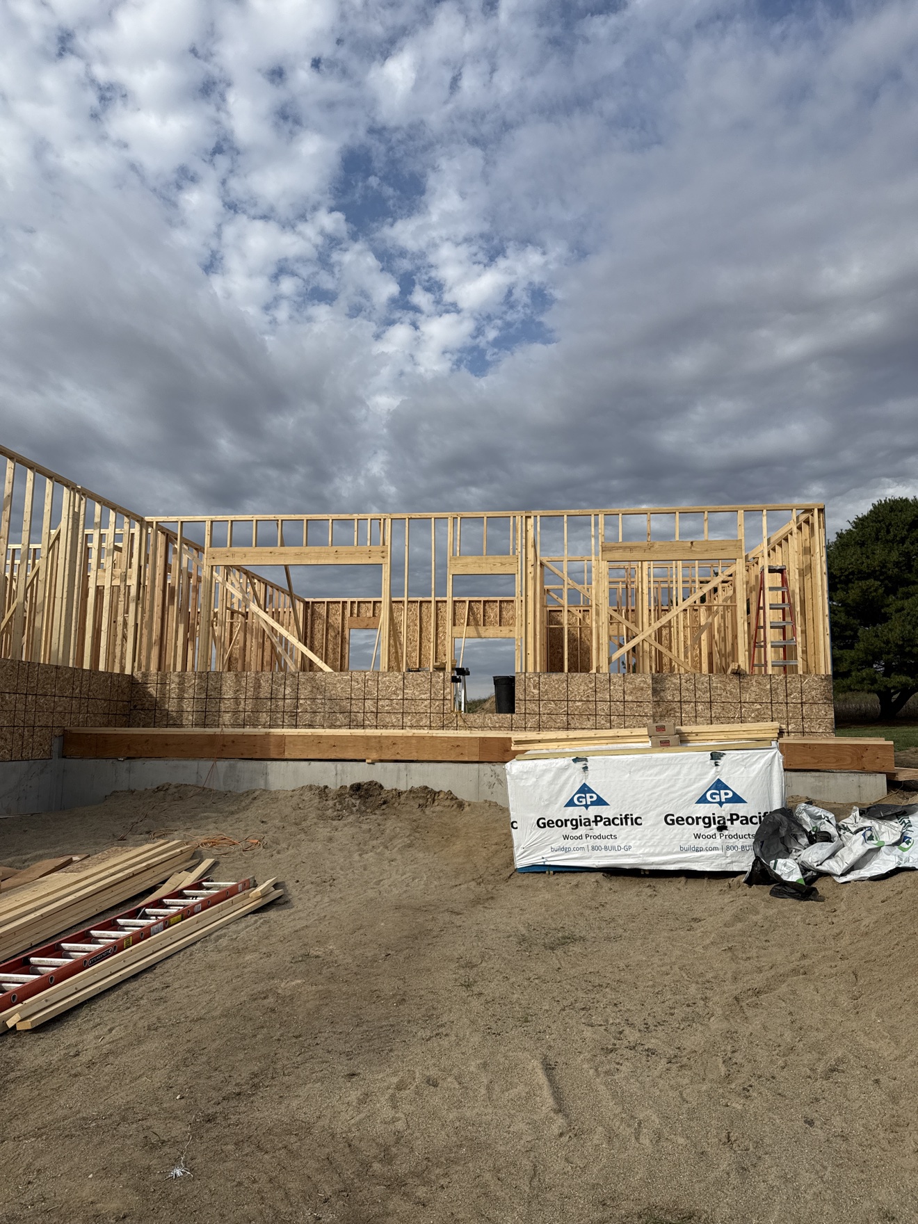 Wide view of wood wall framing under construction beneath a cloudy sky