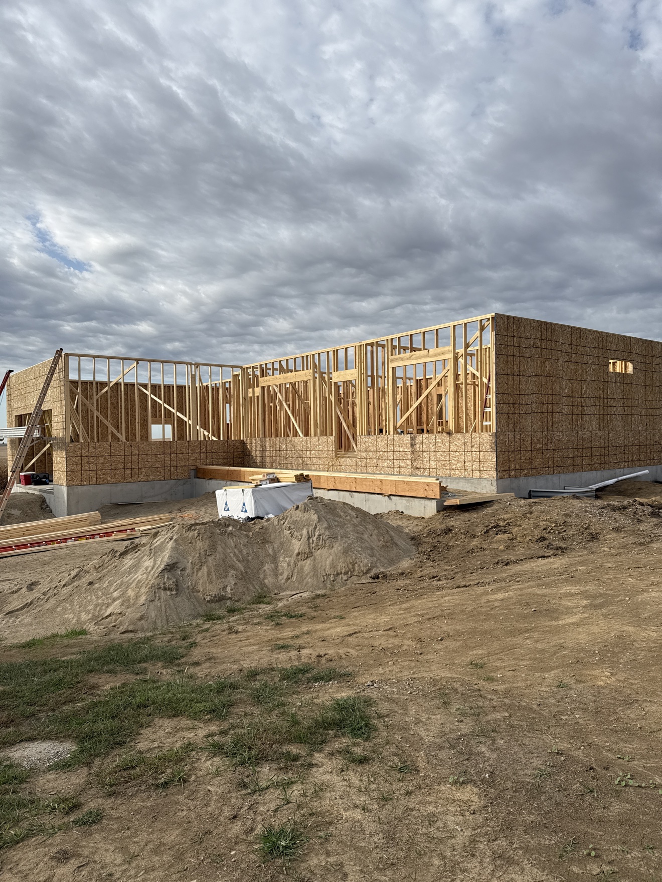Exterior view of a house under construction with wood studs and sheathing