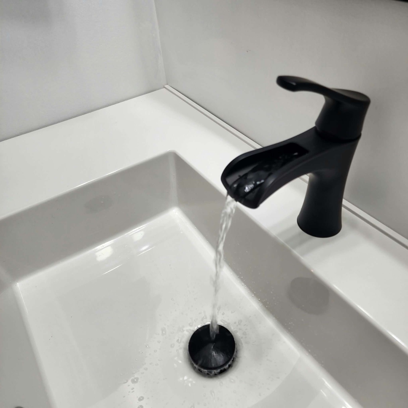 White bathroom sink with matte black faucet and matching drain