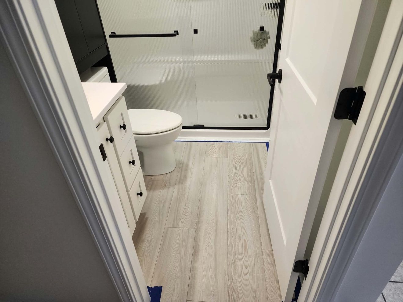 Remodeled bathroom with tub, vanity, toilet, and light wood-look flooring