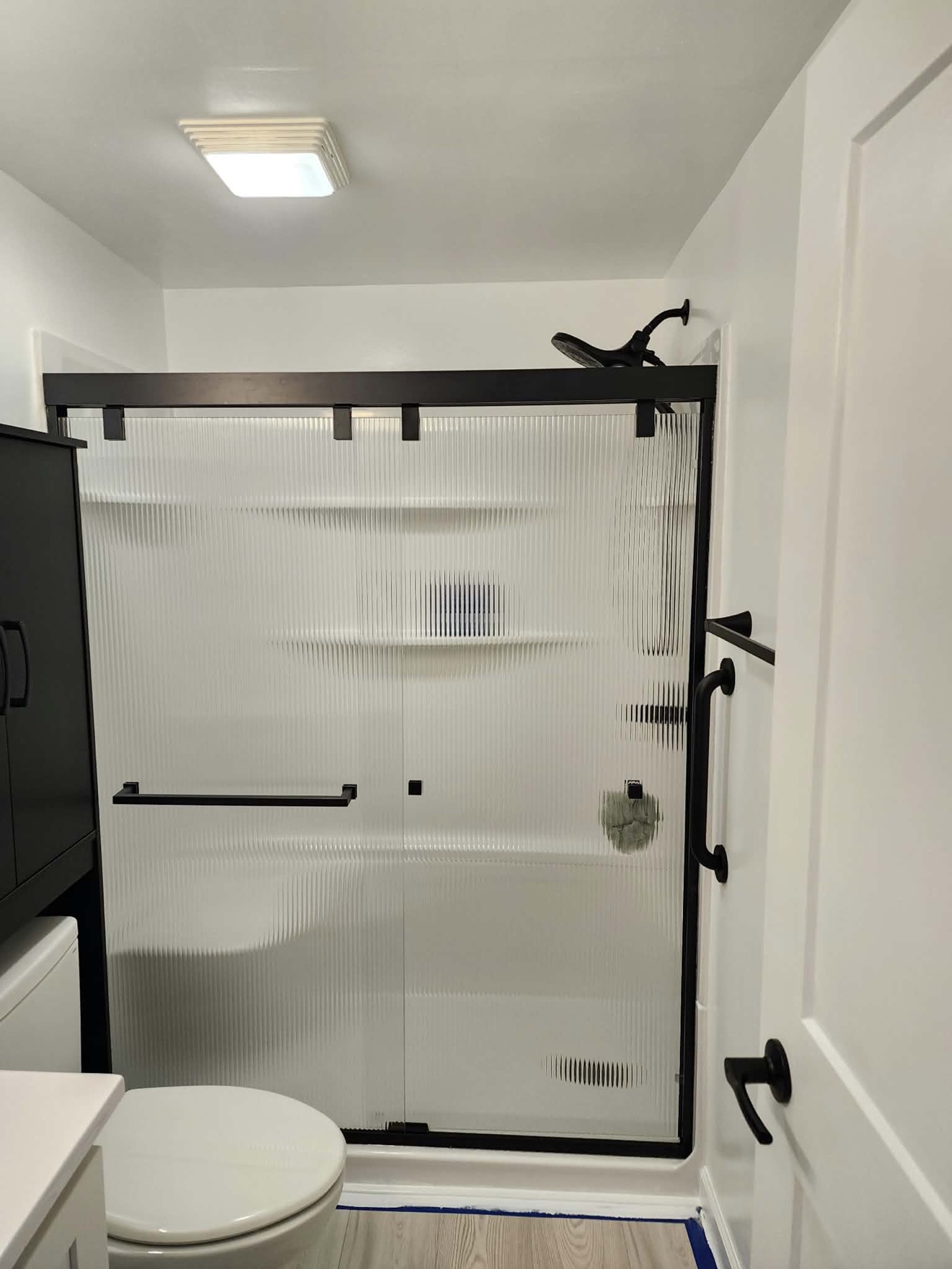 White shower surround with sliding barn-style glass door hardware