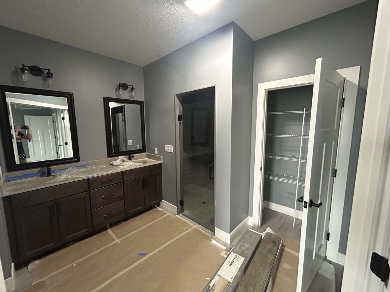 Gray bathroom remodel with double vanity, glass shower, and storage closet