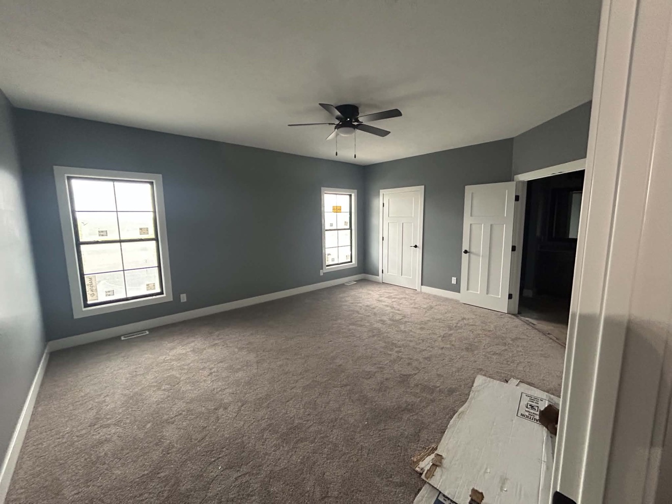 Finished bedroom with gray walls, white trim, carpet, windows, and ceiling fan