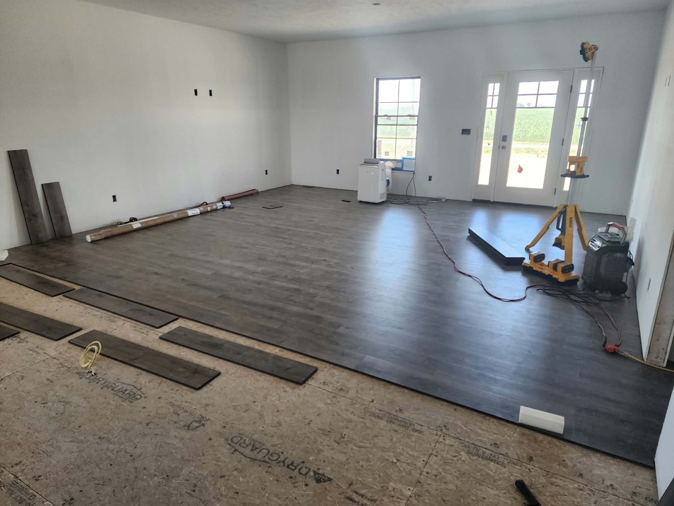 Dark wood-look plank flooring being installed across an open room