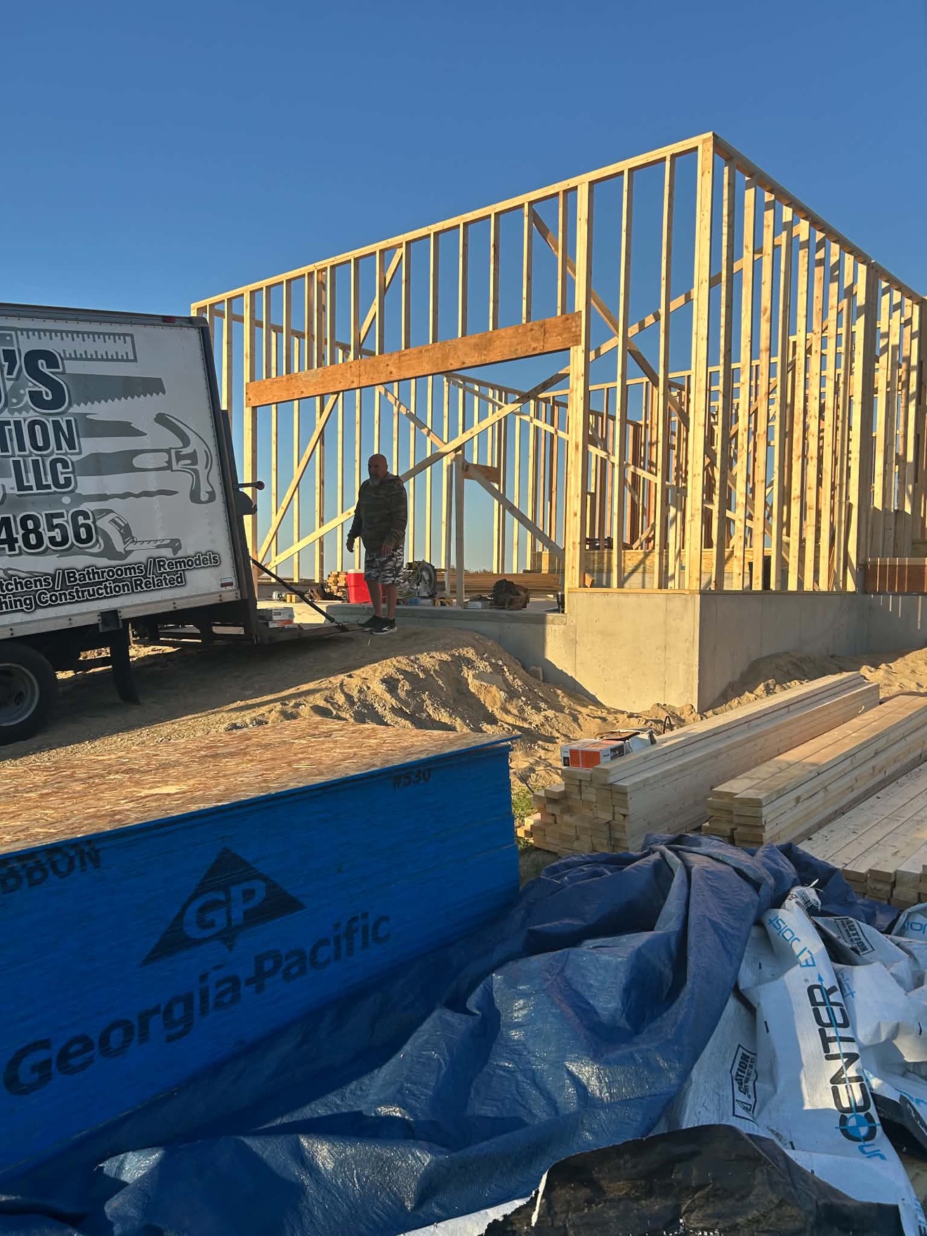 New building framed in wood on a concrete foundation with lumber stacked at the job site