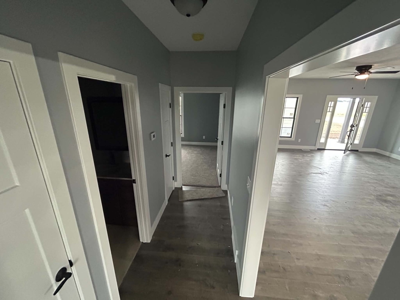 Finished hallway connecting a carpeted bedroom and open living area with plank flooring