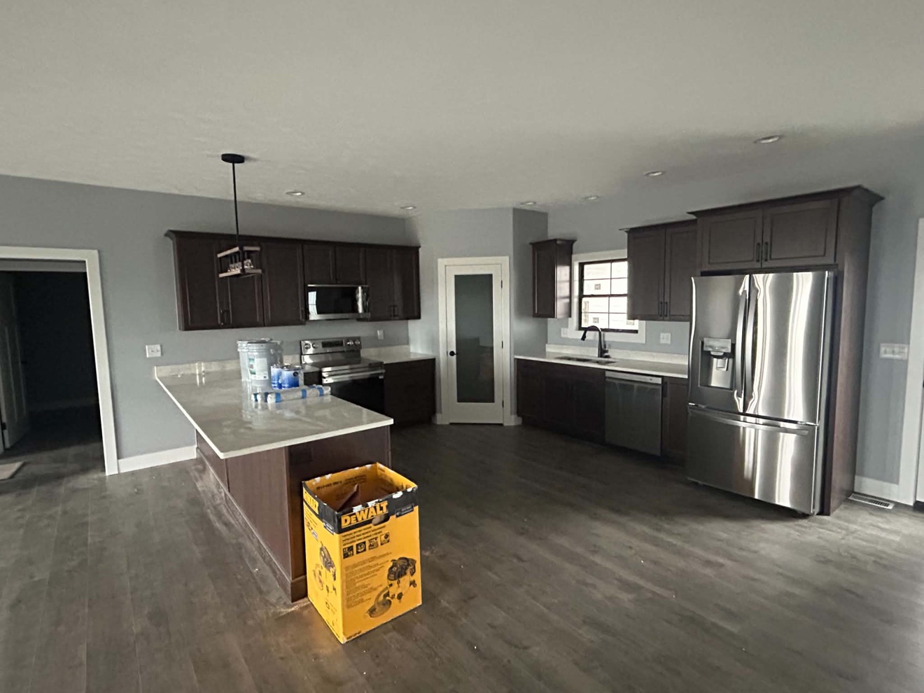 Finished kitchen with dark cabinets, stone counters, stainless appliances, and wide island