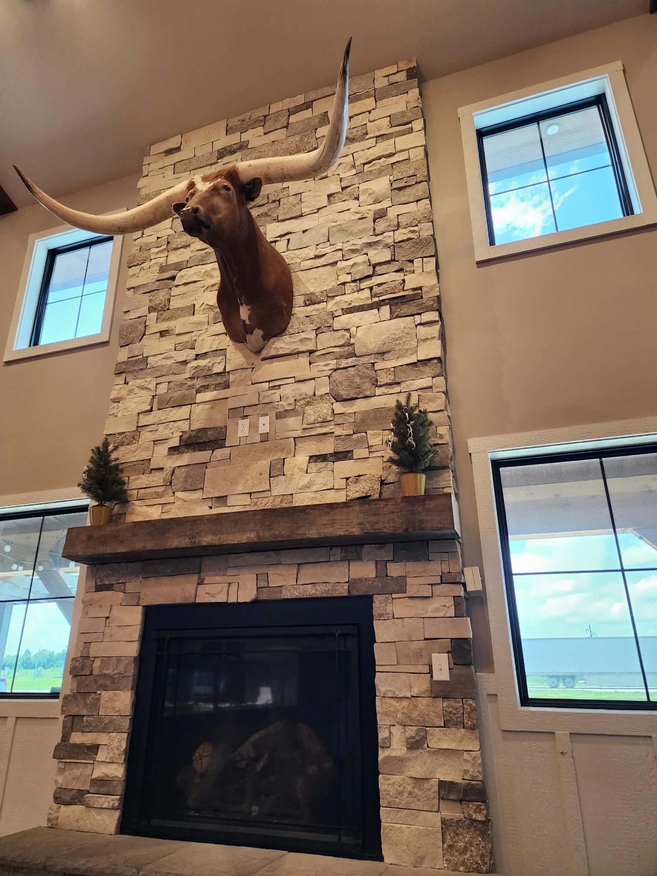 Two-story stone fireplace with a dark firebox and wood mantel